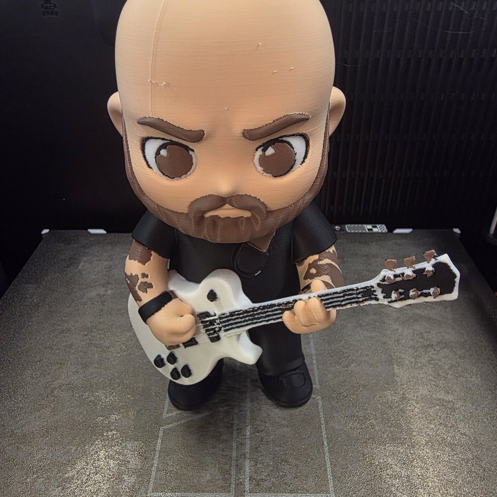 The finished 3D printed chibi figure standing on the print bed, painted in multiple filament colors