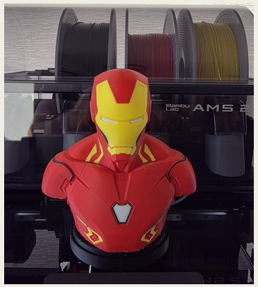 The finished Iron Man bust printed in color in front of a Bambu AMS